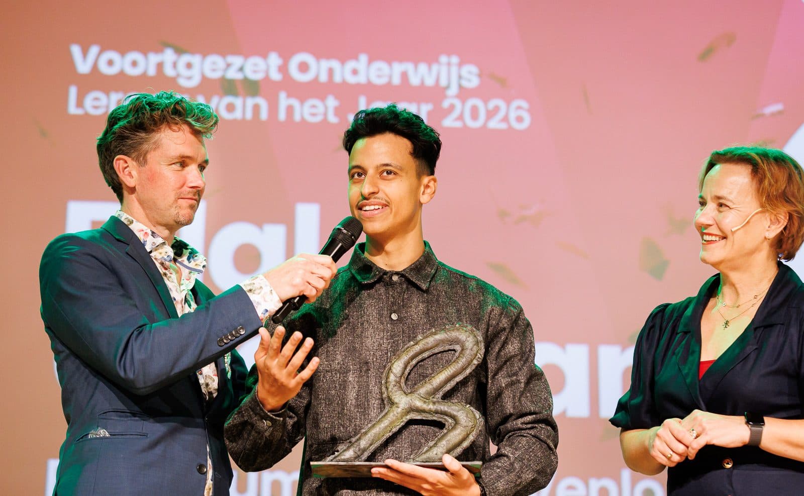 Bilal spreekt met de trofee in zijn handen in de microfoon op het podium
