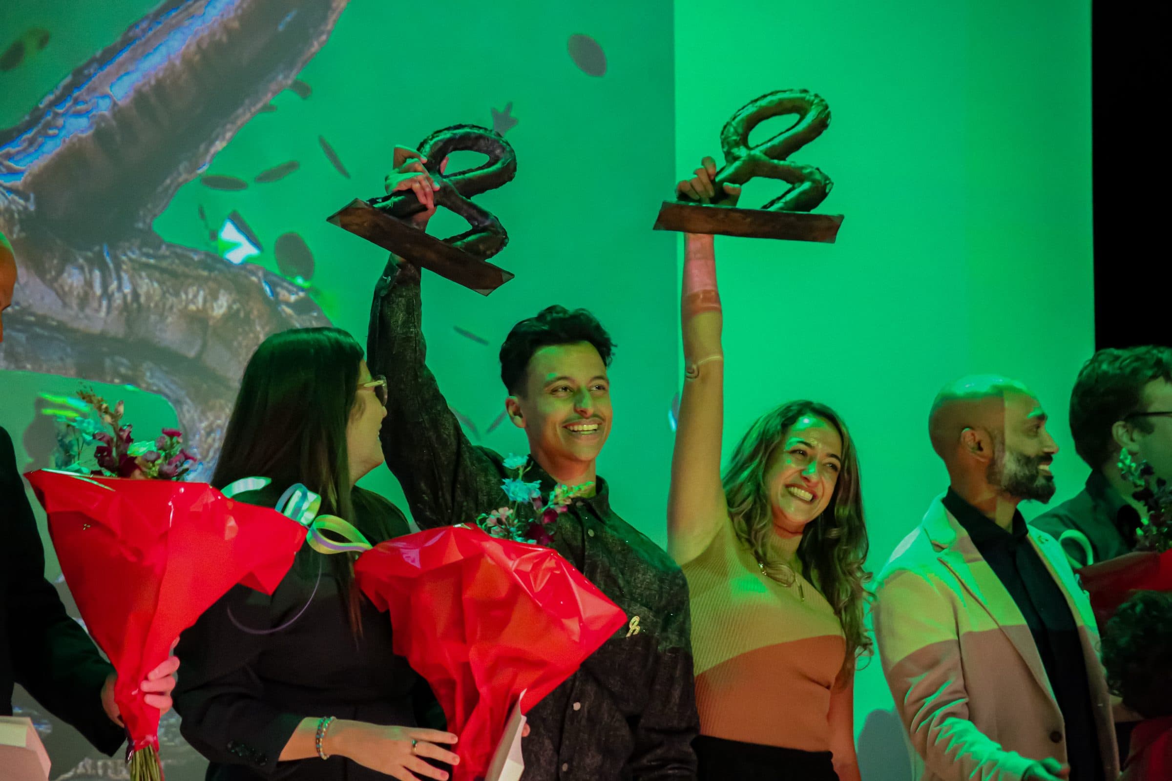 Bilal en de andere winnaars houden hun trofeeën omhoog op het groene podium