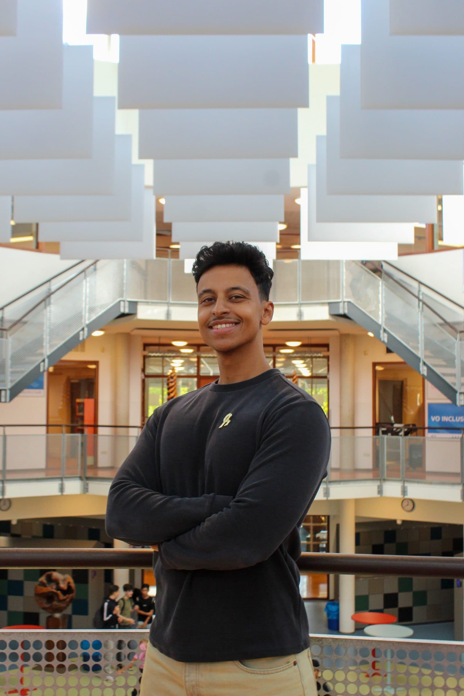 Bilal met gekruiste armen op de galerij van het atrium van het Blariacumcollege
